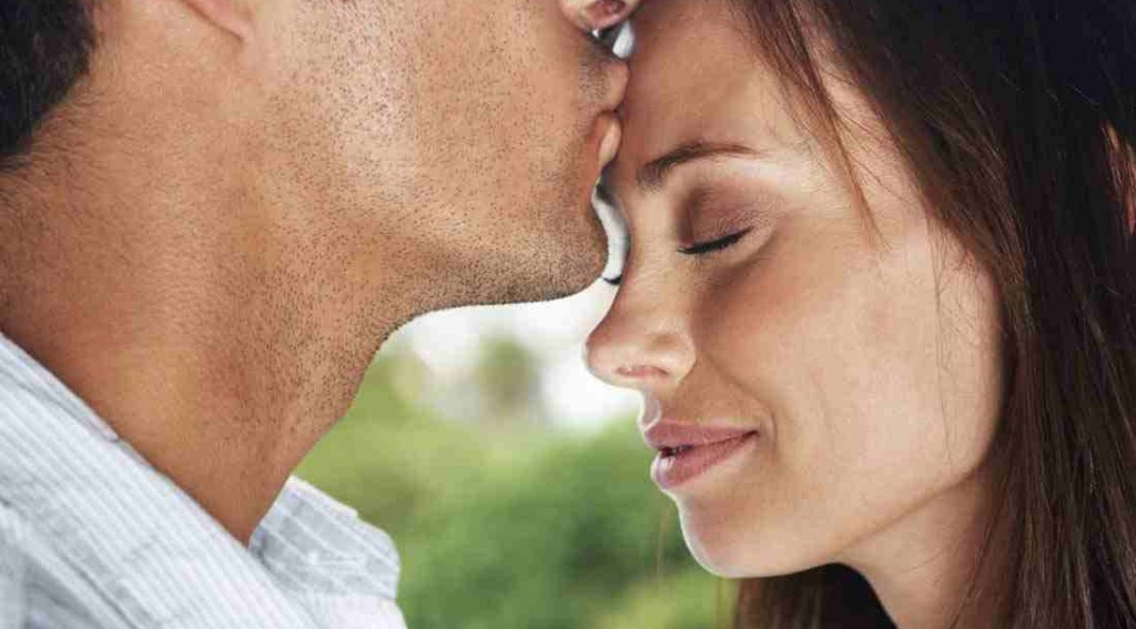 man kissing woman on forehead